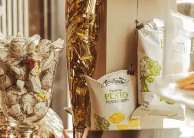 Auf einer Theke stehen Gläser mit verpackten Süßigkeiten und eine Tüte Palatine Pesto Chips. Die Szene hat ein warmes, klassisches Flair mit ordentlich angeordneten Snacks und Leckereien.